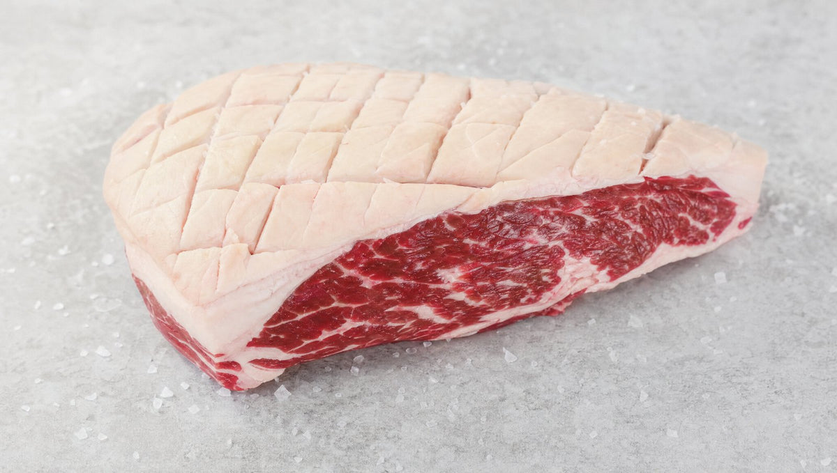 Raw picanha rump cap with a scored fat cap and marbled beef